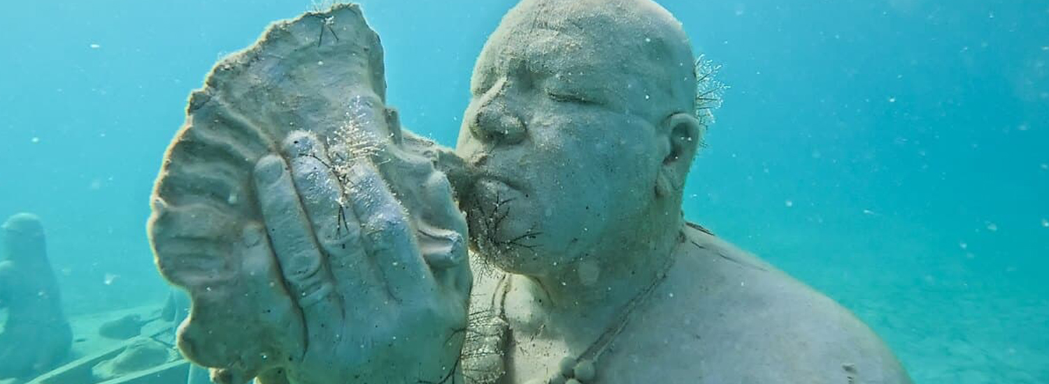 underwater statue of man blowing on shell underwater statue of man blowing on shell